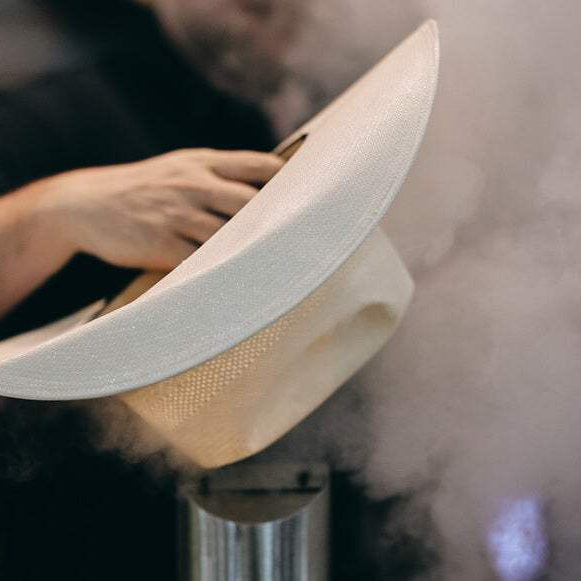 Shaping a straw cowboy hat with steam